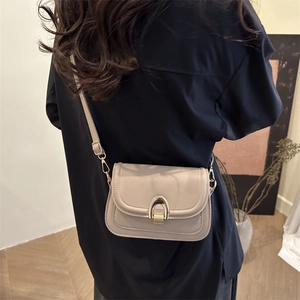 Minimalist beige crossbody bag with gold metallic buckle shown on shoulder back view