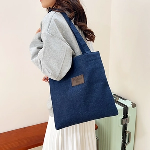 Deep blue denim canvas tote bag with brown leather patch, ideal for daily commute or campus