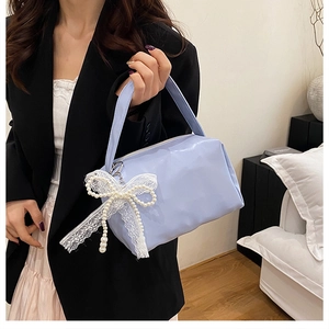 Detail of light blue faux leather handbag with lace bow and pearl charm decoration