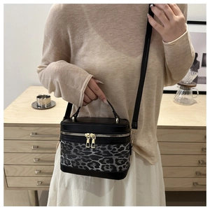 Sac boîte chic à motif léopard avec zips dorés porté par un mannequin pour le style