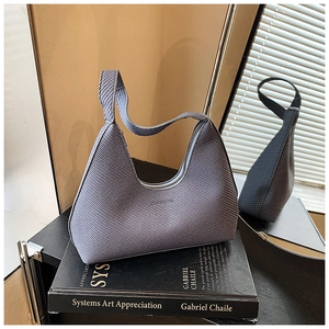 Détail du sac hobo tissé avec poignée et fermeture éclair posé sur un livre noir