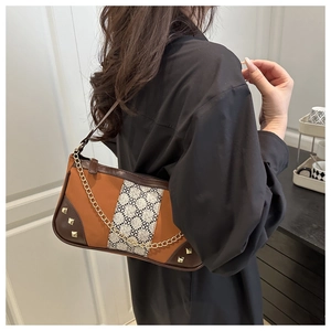 Close-up of vintage baguette bag with floral fabric and gold stud detailing on a model