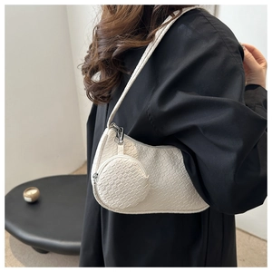 Detail of cream woven underarm bag with matching round coin purse on a shoulder strap