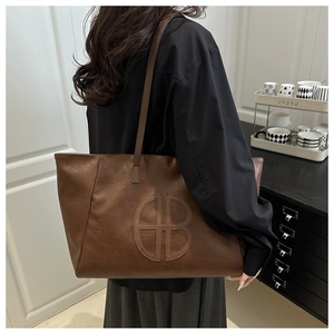Detail of soft brown leather tote bag featuring a large embossed B letter design