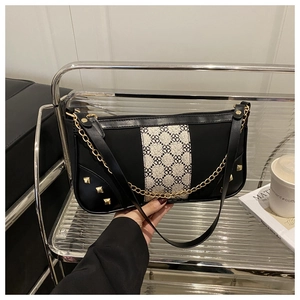 Detail of black leather underarm bag with gold studs and clover print ribbon