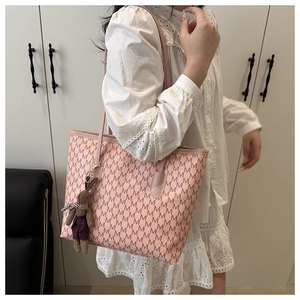 Detailed side view of pink tote bag with M patterns and cute bunny charm on model
