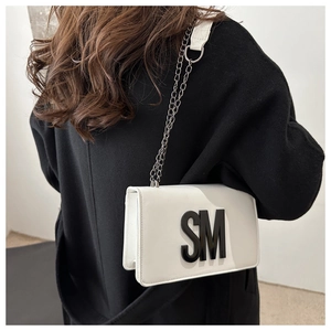 Détail du sac bandoulière blanc avec logo SM noir et bandoulière en chaîne métallique