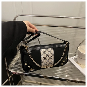 Close-up of retro black square underarm bag with beige floral canvas and gold chain