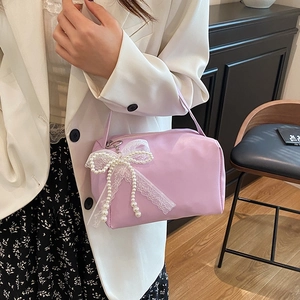 Lavender purple handbag with lace bow and pearl charm held by woman in blazer