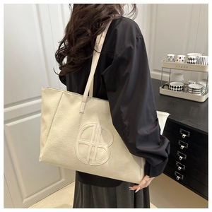 Detail of cream tote bag featuring textured lychee leather and embroidered BB logo