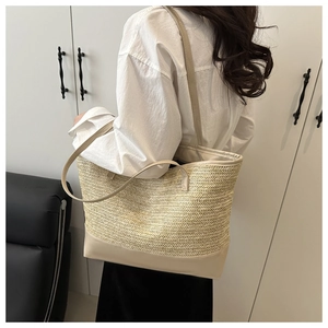 Detailed shot of a beige straw tote bag with leather base carried by a woman