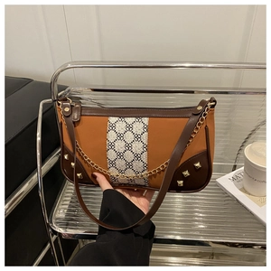 Detail view of two-tone brown and orange shoulder bag with golden studs and chain strap