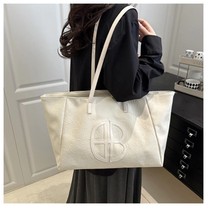 Detail of white tote bag featuring pleated texture and circular cutout logo ornament