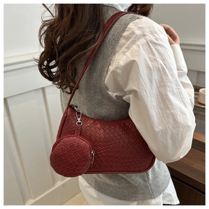 Detail of dark red woven shoulder bag with small round coin purse on a shoulder strap