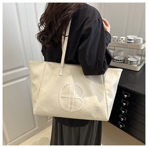 Detail view of the beige oversized tote bag with stitched logo and wrinkled texture