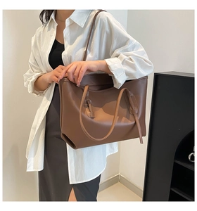 Brown leather tote bag worn by model on shoulder showing large capacity and smooth texture