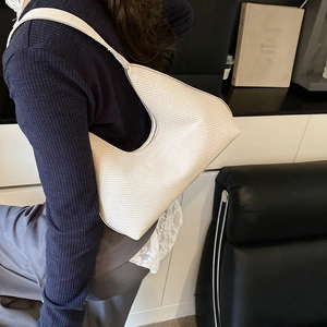 Sac à bandoulière en croissant crème minimaliste avec texture tissée porté par modèle