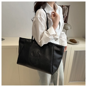 Close-up of black tote bag featuring double B embossed logo and lychee grain texture
