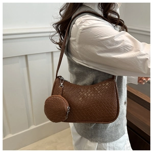 Detailed look at caramel brown woven half-moon shoulder bag with a round coin pouch charm