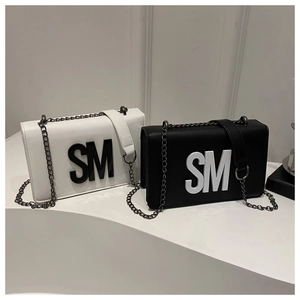 Vue détaillée du logo SM et des bandoulières en chaîne sur les sacs à rabat noir et blanc