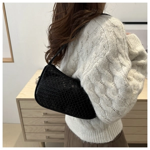 Close-up of black crocodile texture faux leather on a retro crescent underarm bag