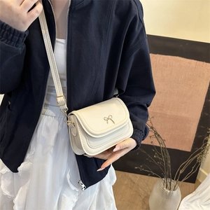 Chic beige square crossbody bag with gold bow detail and adjustable shoulder strap