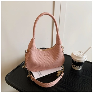 Detail der rosa Handtasche mit Webstruktur, Goldkette und elegantem Tragegriff