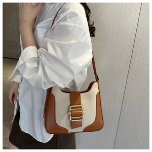 Détail du sac bandoulière rétro en toile et cuir marron avec boucle dorée sur modèle