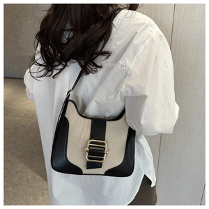 Détail du sac sous le bras en toile vintage avec bordure en cuir noir et boucle dorée