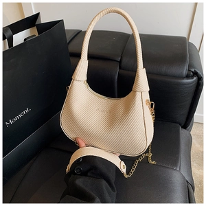 Nahaufnahme der beige geflochtenen Hobo-Tasche mit Knotengriff und Goldkette