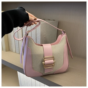 Détail des coutures en cuir rose et toile beige avec boucle en métal doré sur le sac