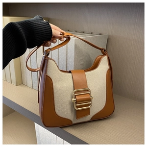Détail du sac cabas vintage avec boucle dorée sur cuir marron et toile beige