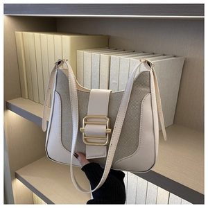 Gros plan d'un sac en cuir et tissu orné d'une grande boucle en métal doré brillant