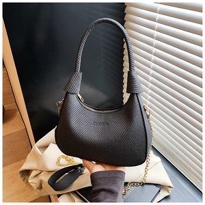 Detail der schwarzen geflochtenen Crescent-Tasche mit Goldkette und breitem Gurt