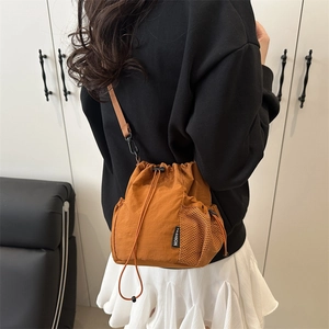Bolso saco naranja con cierre de cordón y etiqueta de moda visto de perfil