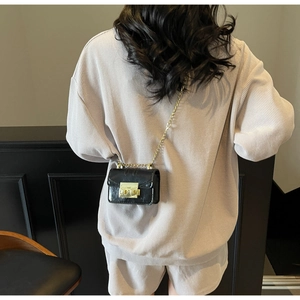 Détail du petit sac bandoulière en cuir noir avec chaîne dorée et fermoir carré chic