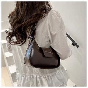 Model wearing dark brown semi-moon shoulder bag with adjustable strap and white text logo