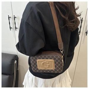 Détail du sac bandoulière vintage avec logo embossé et large sangle tissée