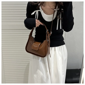 Detail of a brown leather crescent shoulder bag with white printed logo and buckle strap