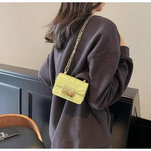 Détail du sac bandoulière en cuir verni vert fluo avec chaîne dorée et boucle