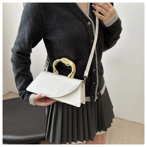 Detail of white leather mini square bag with golden curved metal handle and accordion sides