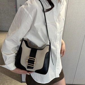 Sac hobo rétro en toile beige et cuir noir porté par un mannequin en studio