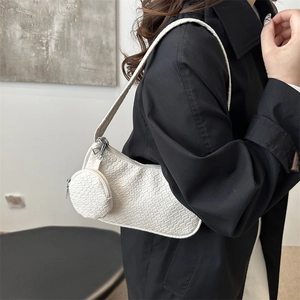 Minimalist white textured underarm bag with a round coin purse on a model's shoulder