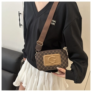 Détail d'un sac caméra vintage à monogramme marron avec bandoulière sur un mannequin