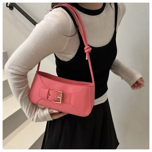 Detail of pink croissant bag with large gold buckle and knotted shoulder strap detail