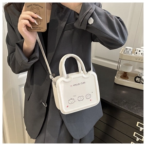 Close-up of white crossbody bag with cute bear illustration on gray blazer outfit