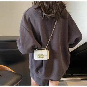 Détail d'un mini sac à bandoulière avec boucle dorée sur une texture en tissu gaufré