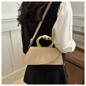 Detail of beige trapezoid handbag with unique gold liquid metal handle and suede texture