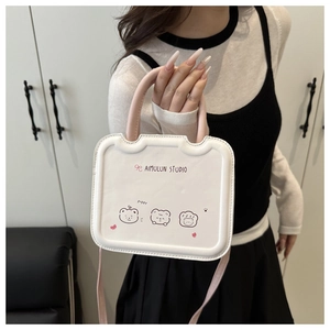 Detail of white mini square bag featuring cartoon bear print and pink top handles