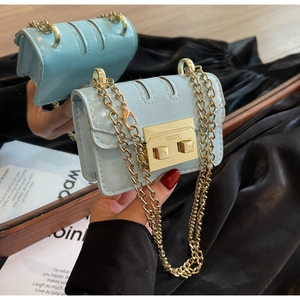 Détail du sac à chaîne bleu clair avec fermoir doré carré et reflet sur miroir